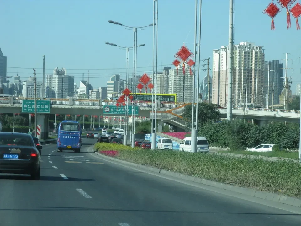 Una vista panoramica di una città cinese con edifici residenziali e una strada trafficata in primo piano.