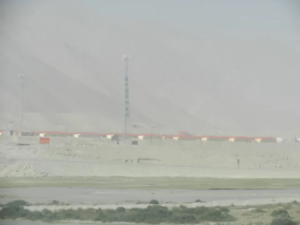 Paesaggio arido con una torre di trasmissione in una vasta area desertica cinese.