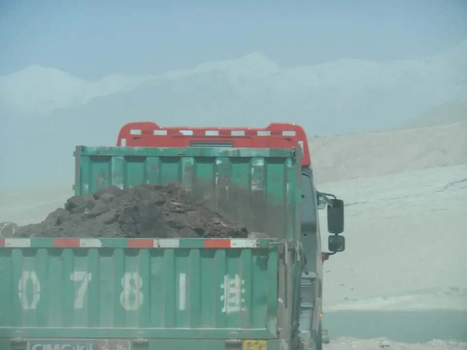Un camion trasporta terra su una strada polverosa in Cina.
