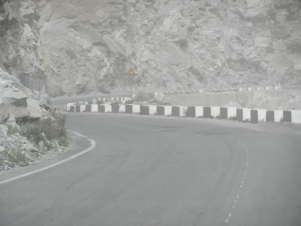Una strada asfaltata serpeggia attraverso un paesaggio montano roccioso in Cina.