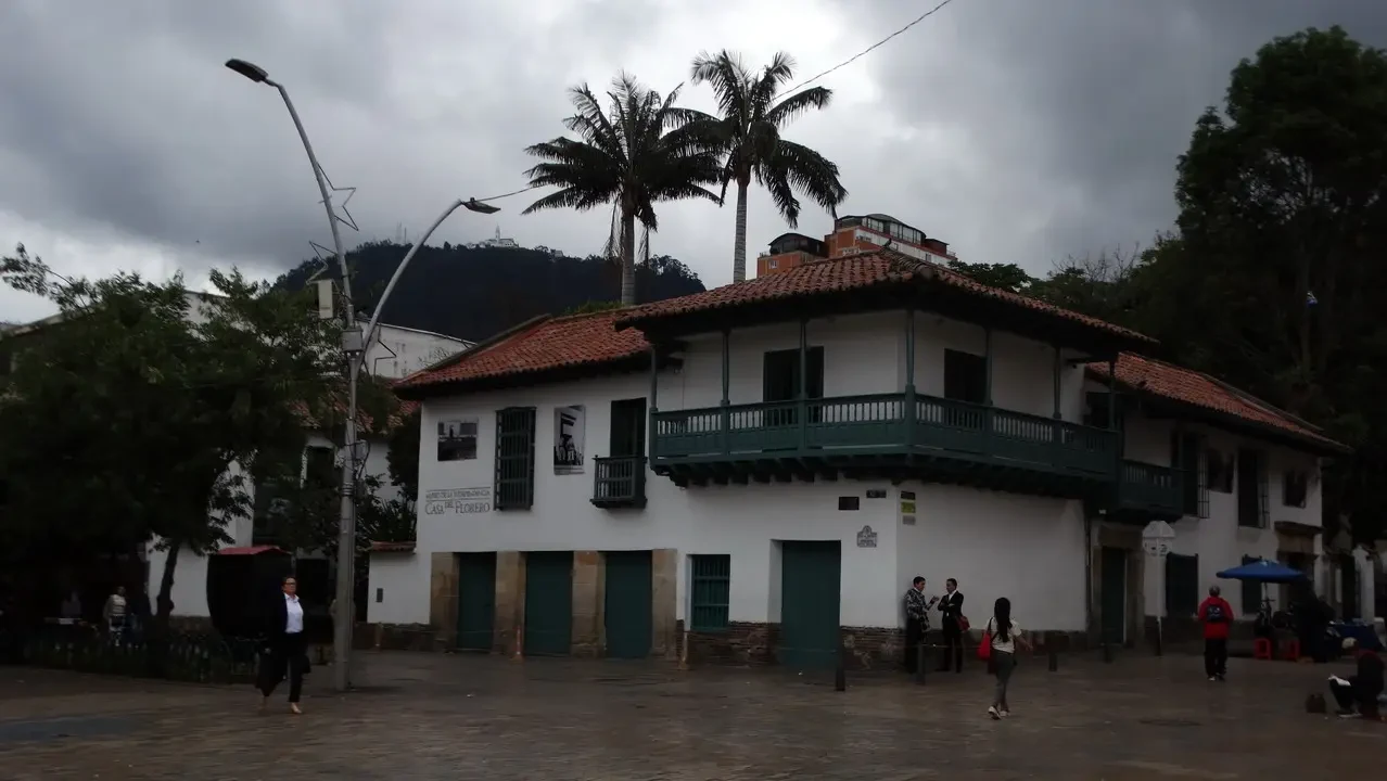 Una casa coloniale con un balcone in primo piano si trova su una collina in Colombia.
