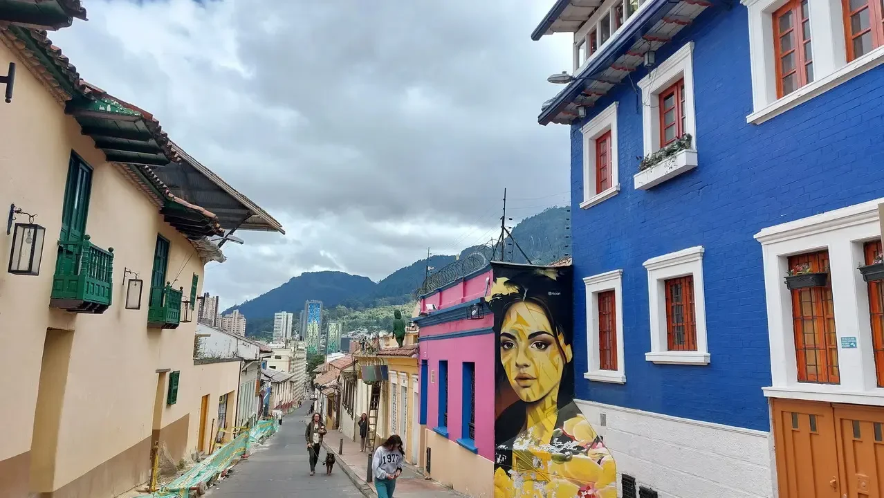 Una strada in una città colombiana con edifici colorati e colline sullo sfondo.