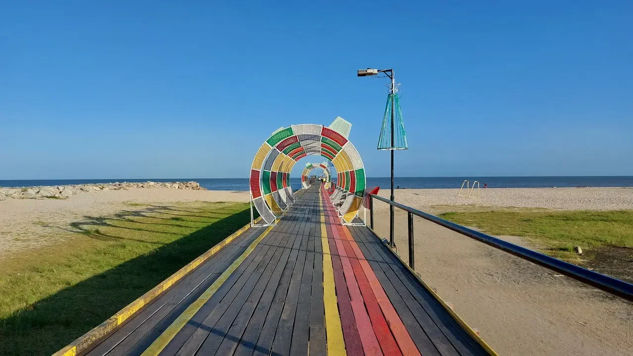 Una passerella colorata si estende lungo la spiaggia verso il mare.