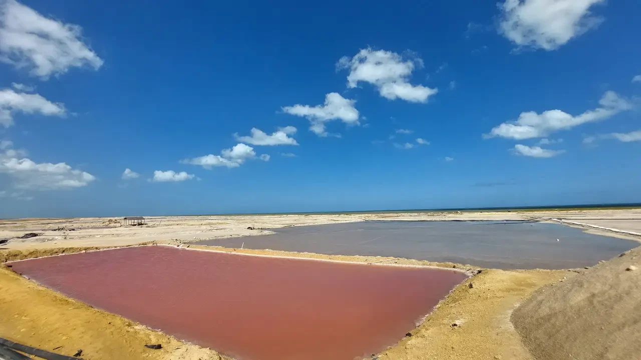 Una vista aerea delle zone umide salmastre in Colombia con acqua di colore rosso e marrone sotto un cielo azzurro.