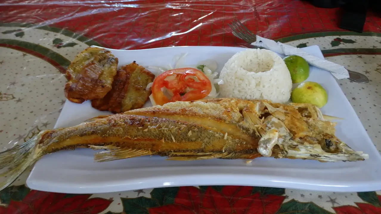 Pesce fritto e accompagnamenti serviti su un piatto in stile colombiano.