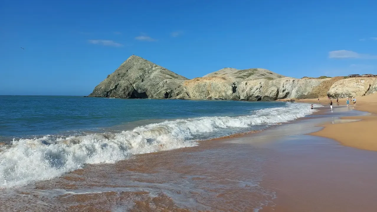 Una spiaggia dorata con rocce costiere e onde blu in Colombia.