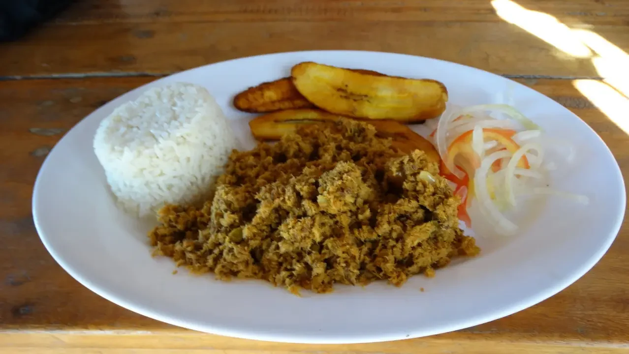 Un piatto di cibo tradizionale colombiano è disposto su un tavolo di legno.