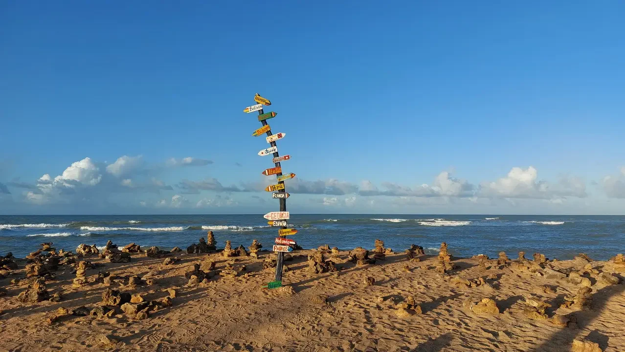 Segnaletica direzionale su una spiaggia costiera in Colombia sotto un cielo azzurro.