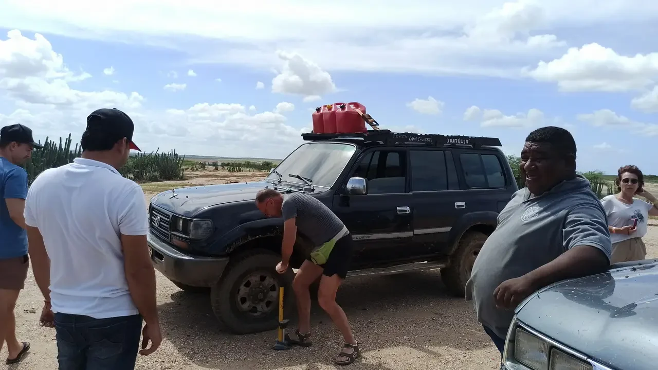 Un gruppo di persone si riunisce attorno a un veicolo fuoristrada in un paesaggio collinare colombiano.