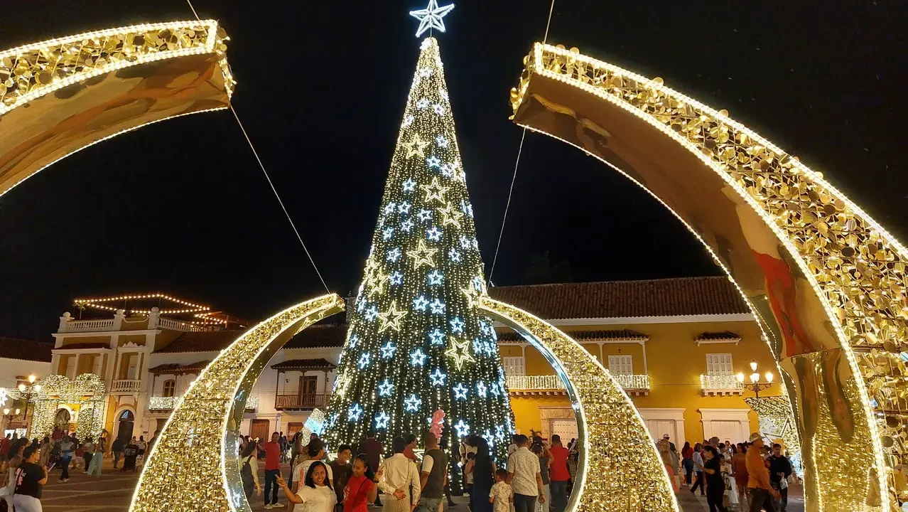 Albero di Natale illuminato con archi dorati in una piazza colombiana.