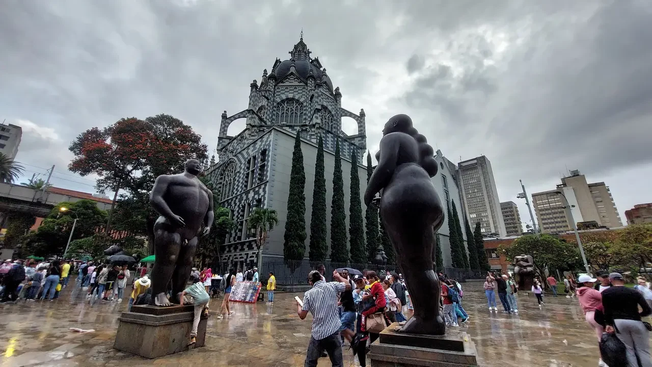 Una piazza con statue monumentali e un edificio storico in una giornata nuvolosa.