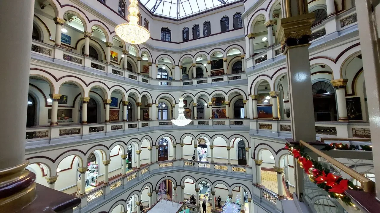 Interno sontuoso di un edificio storico con ampi archi e balaustre decorate.