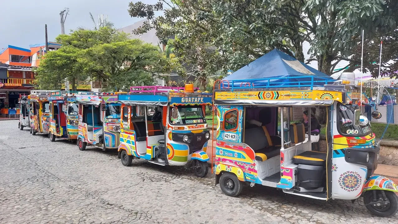 Una fila di mototaxi colorati è parcheggiata su una strada in Colombia.