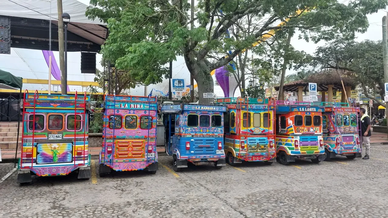 Una fila di autobus colorati è parcheggiata su una strada in Colombia.