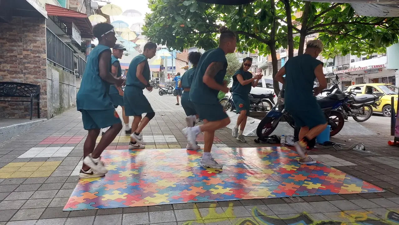 Gruppo di persone cammina su un tappeto colorato in una strada colombiana.