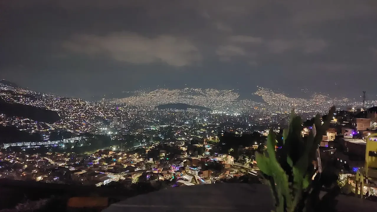 Panorama notturno di una vasta città colombiana illuminata da luci urbane.