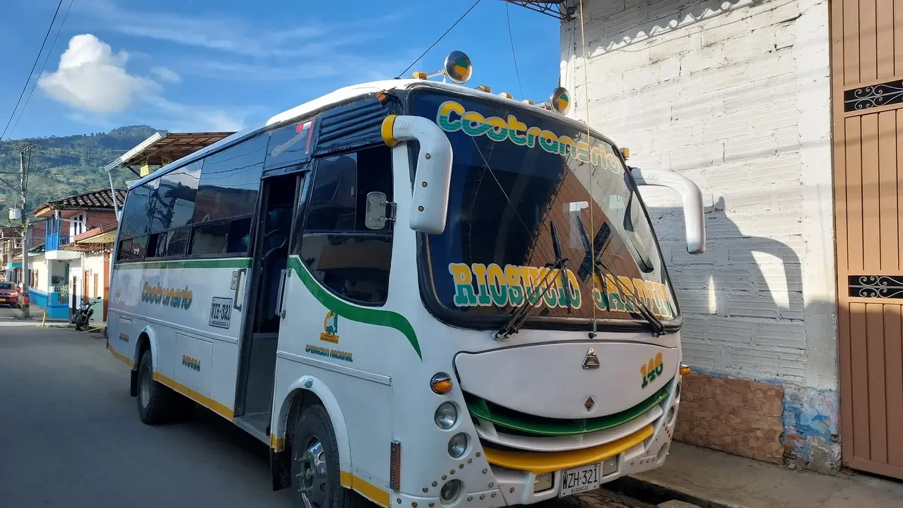 Un autobus bianco viaggia lungo una strada in Colombia.