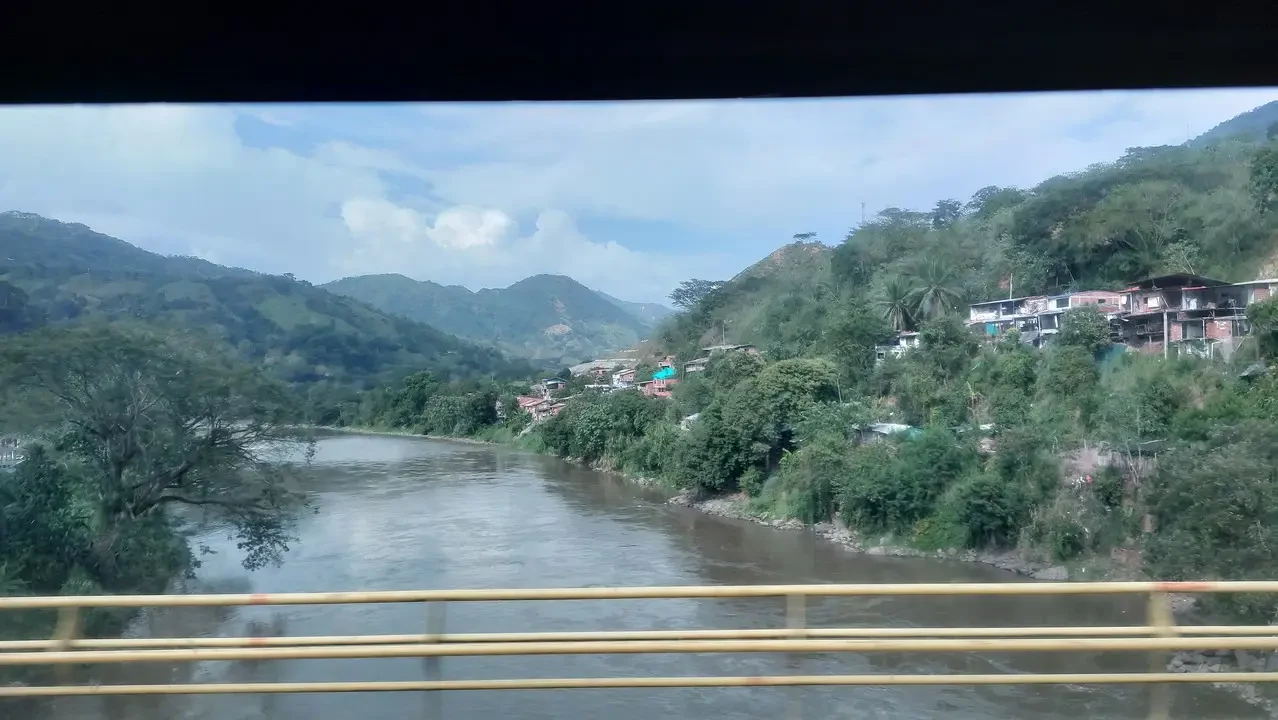 Un fiume ampio scorre attraverso un paesaggio collinare colombiano.
