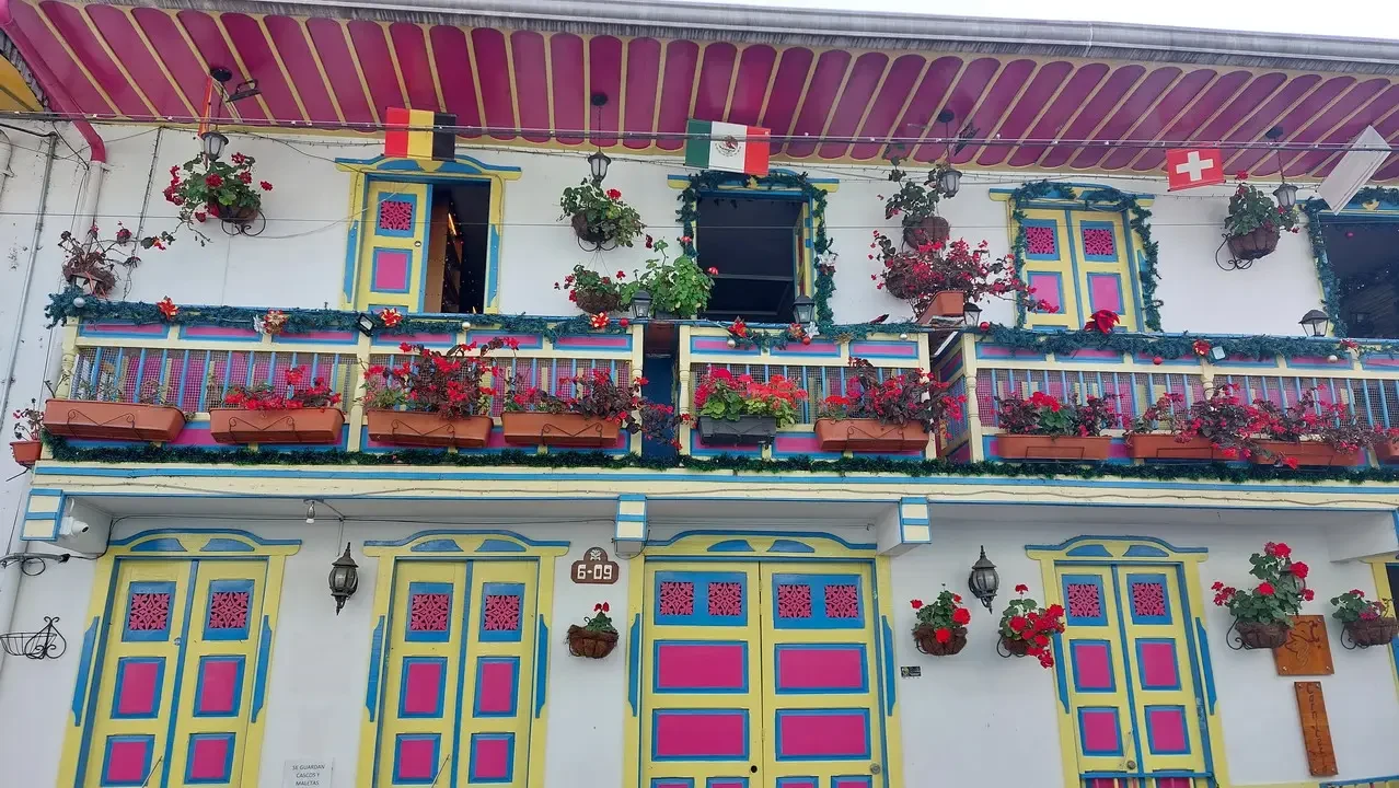 Facciata colorata di una casa in stile coloniale colombiana con balconi fioriti.