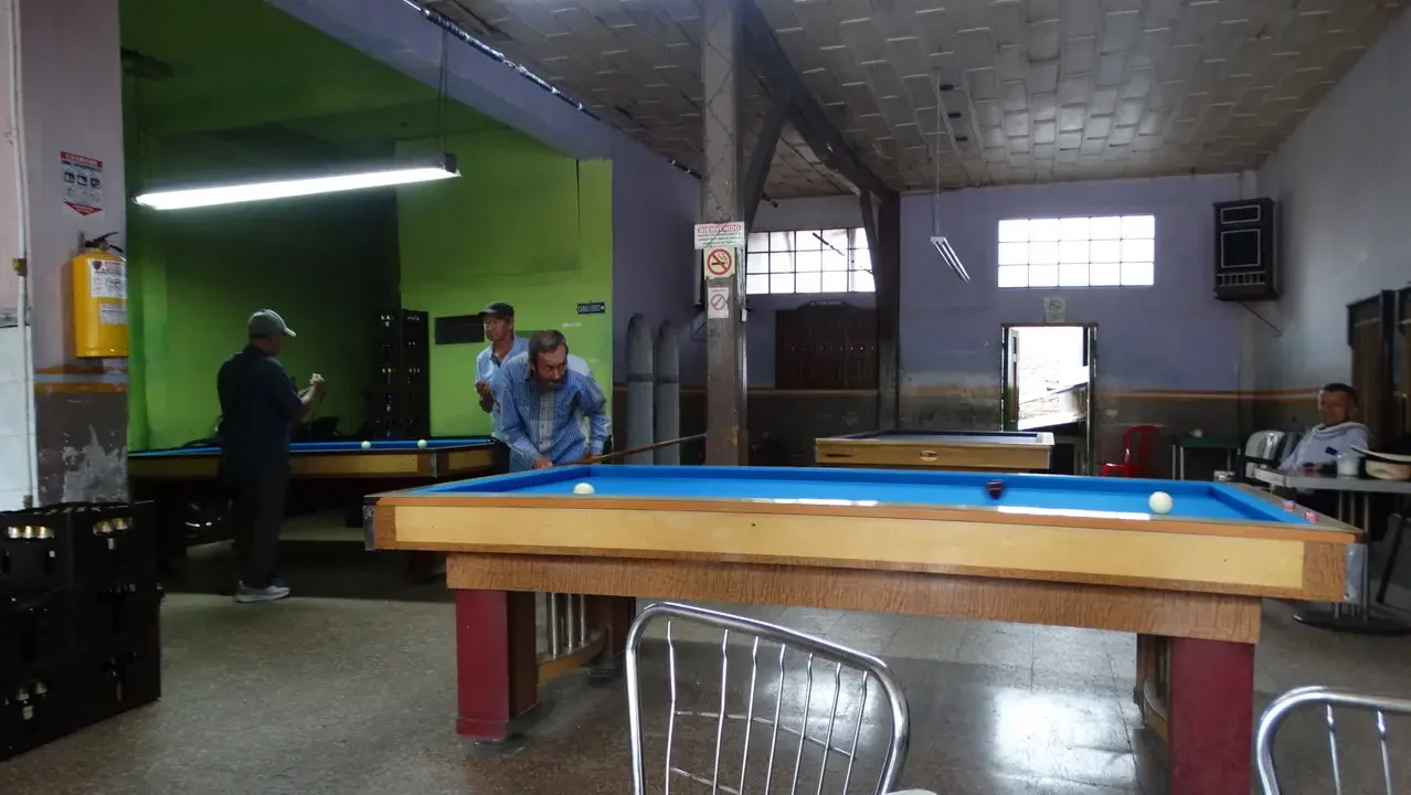 Una sala interna con tavoli da biliardo in un ambiente rustico.