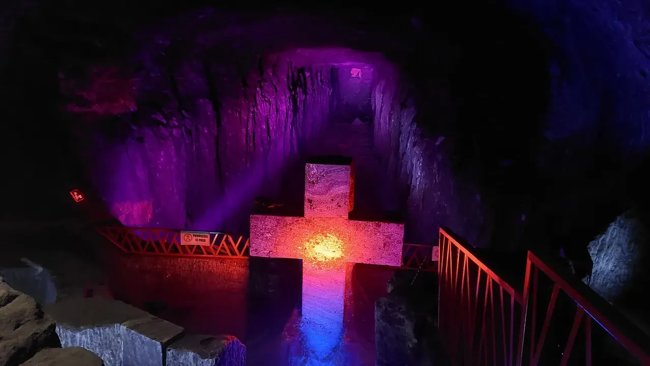Grotta illuminata di viola e rosso con un ponte sopra l'acqua.