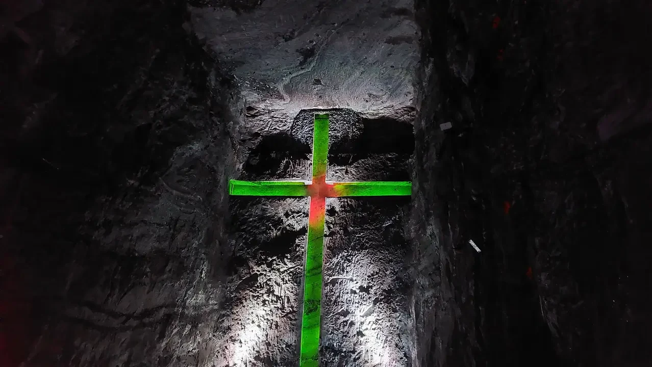 Croce color verde e rossa incastonata nella pietra di un corridoio antico.