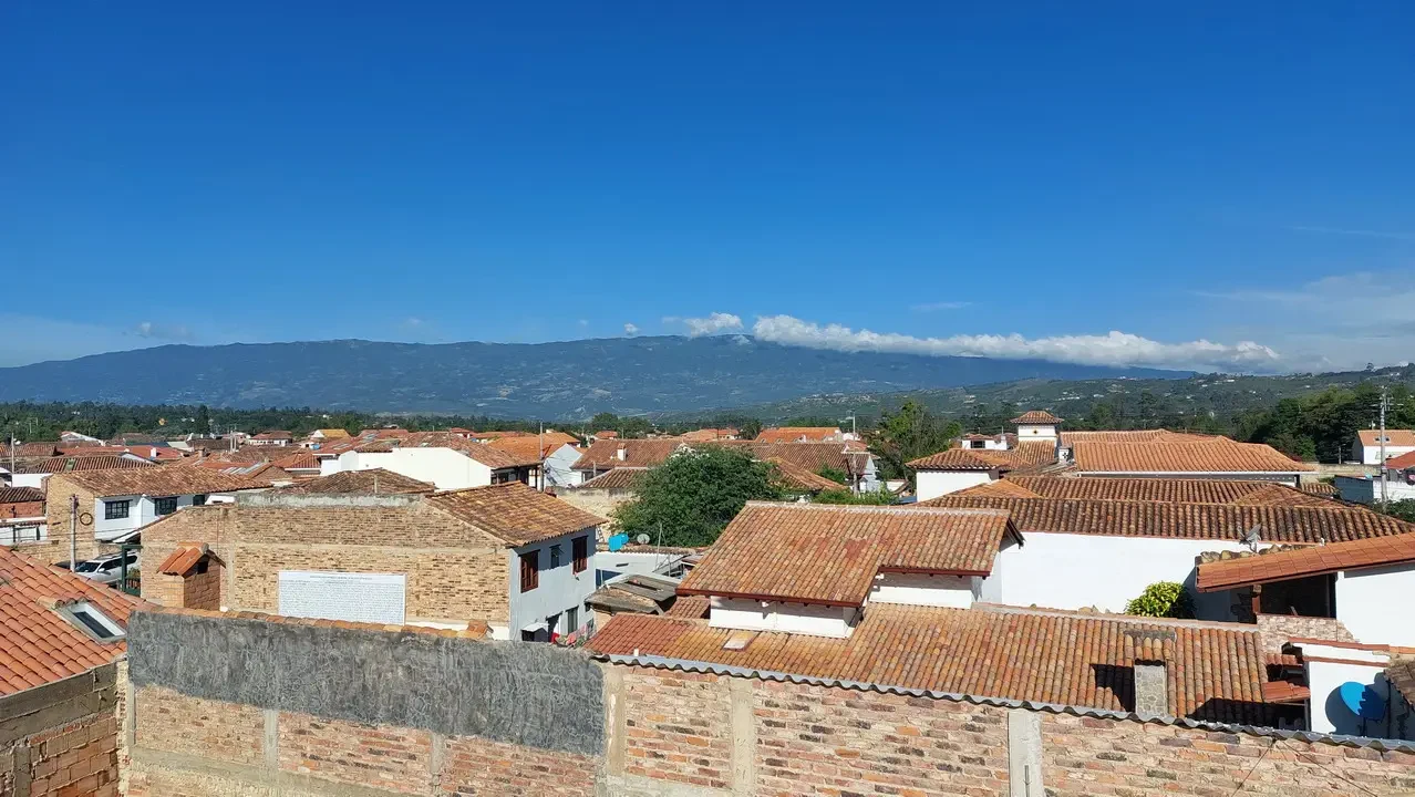 Vista panoramica di tetti rossi e case in una città colombiana con montagne sullo sfondo.