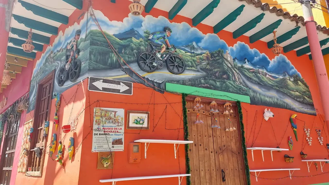 Un murale colorato su un edificio raffigura un paesaggio con persone in bicicletta.