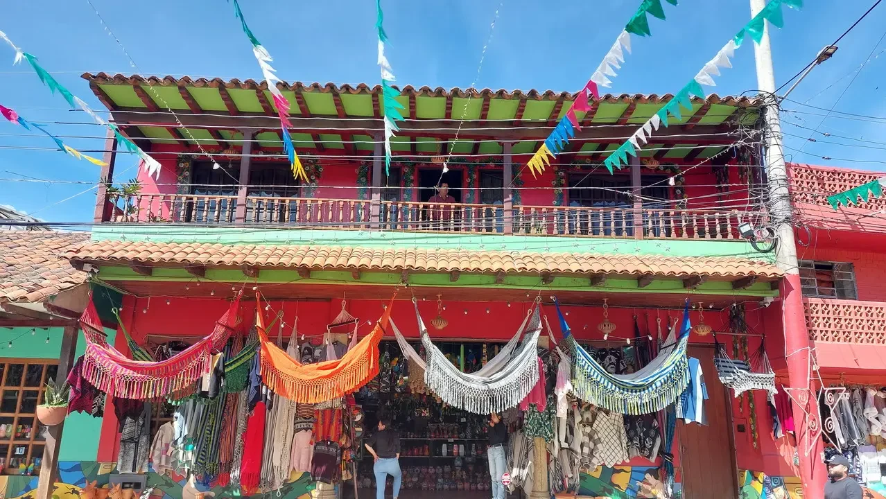 Facciata colorata di un edificio colombiano decorata con tessuti e bandiere tradizionali.