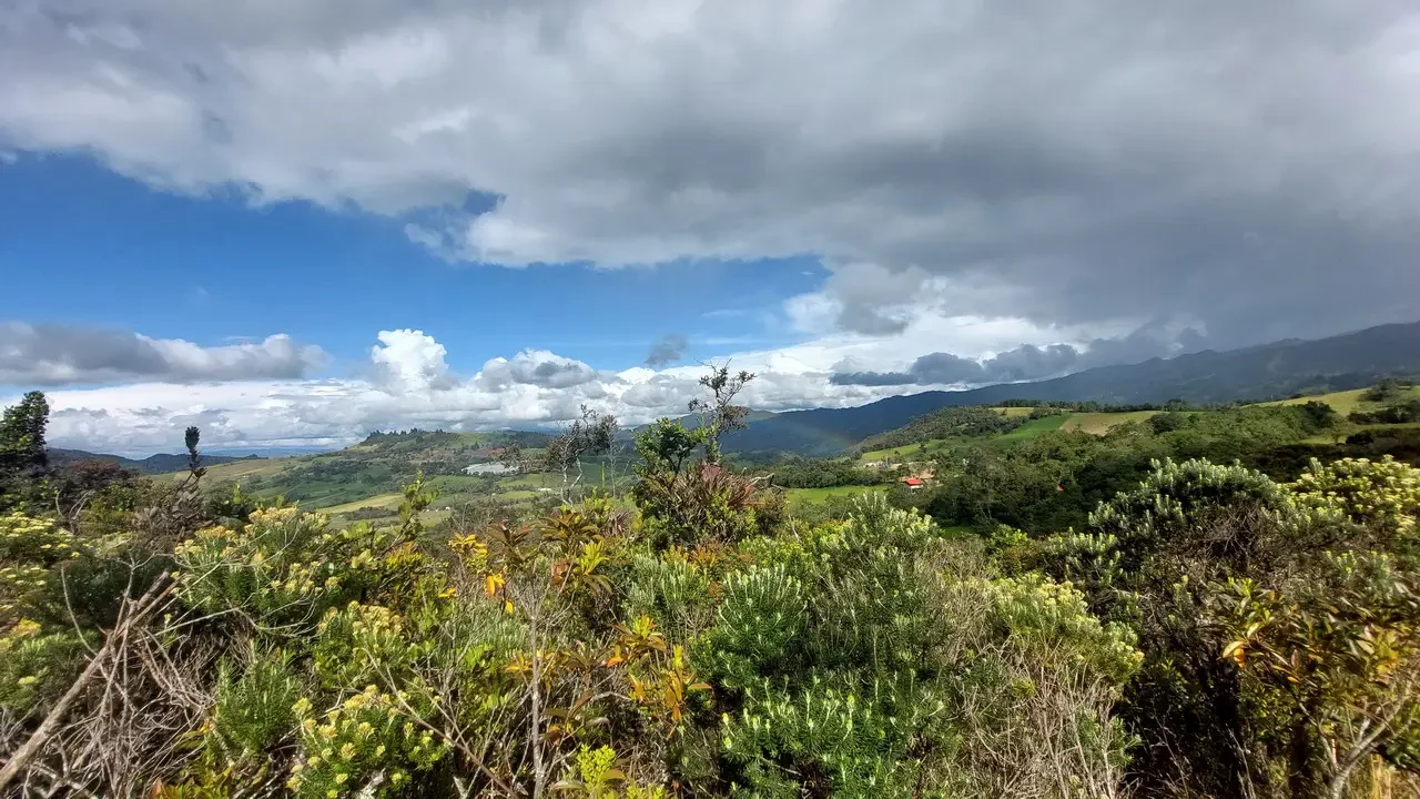 Panorama di colline ondulate e montagne sotto un cielo nuvoloso in Colombia.