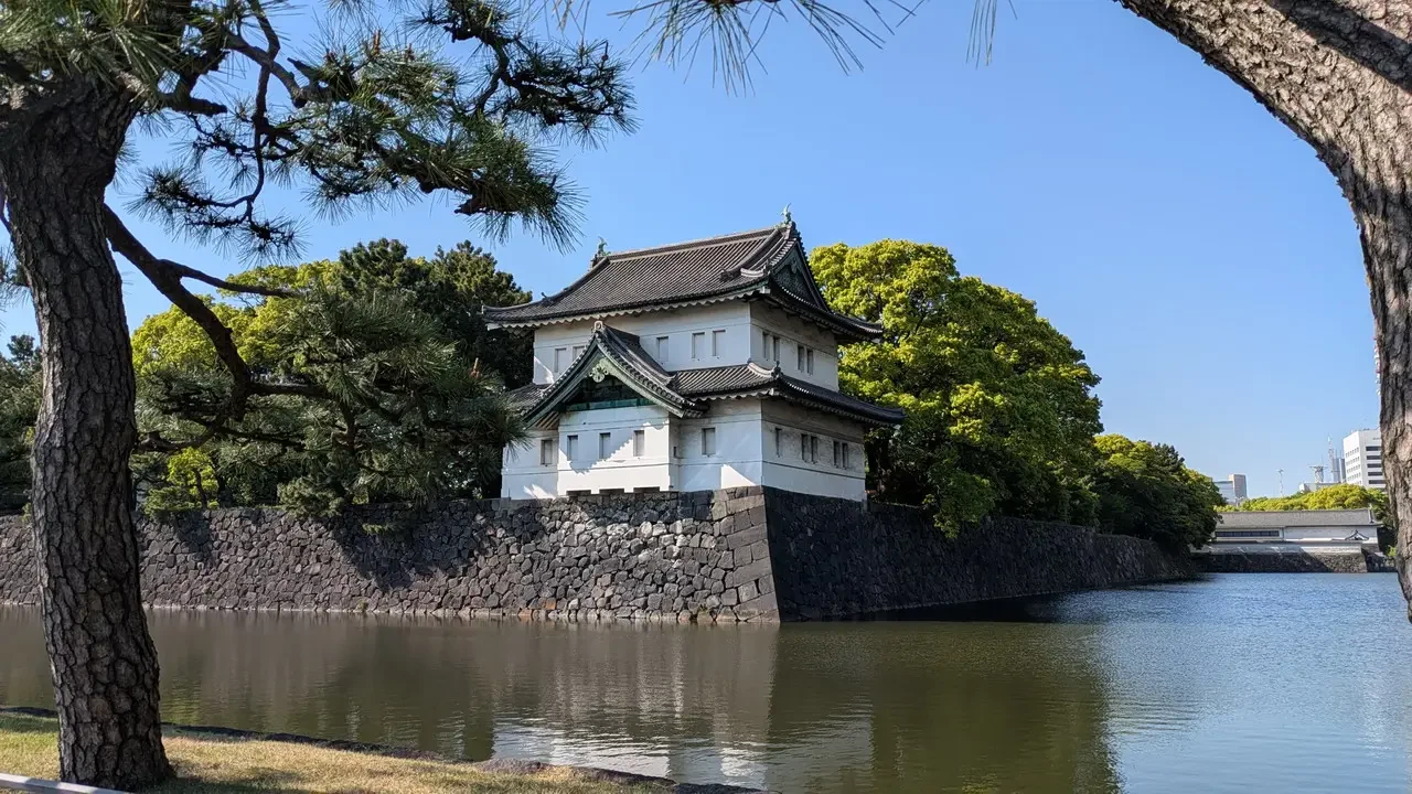 Vista del Palazzo Imperiale di Tokyo attraverso alberi e un canale.