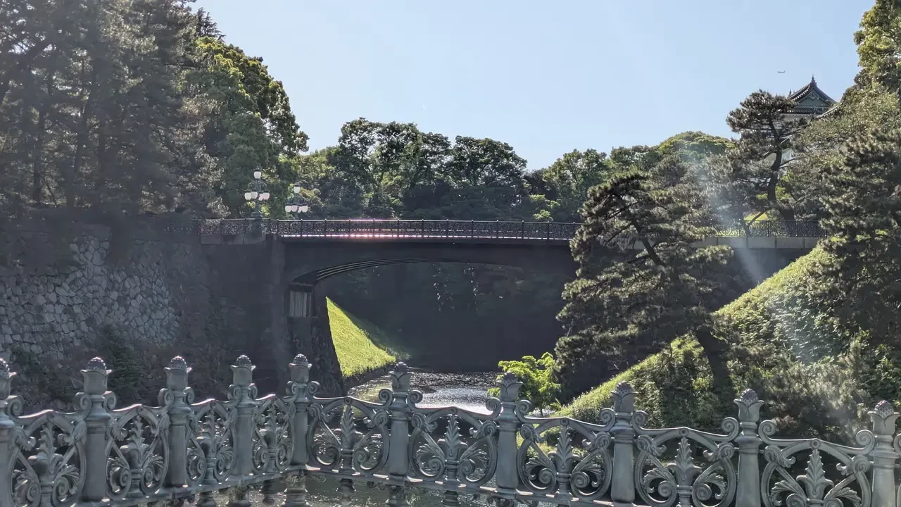 Ponte storico immerso nel verde di un parco giapponese.