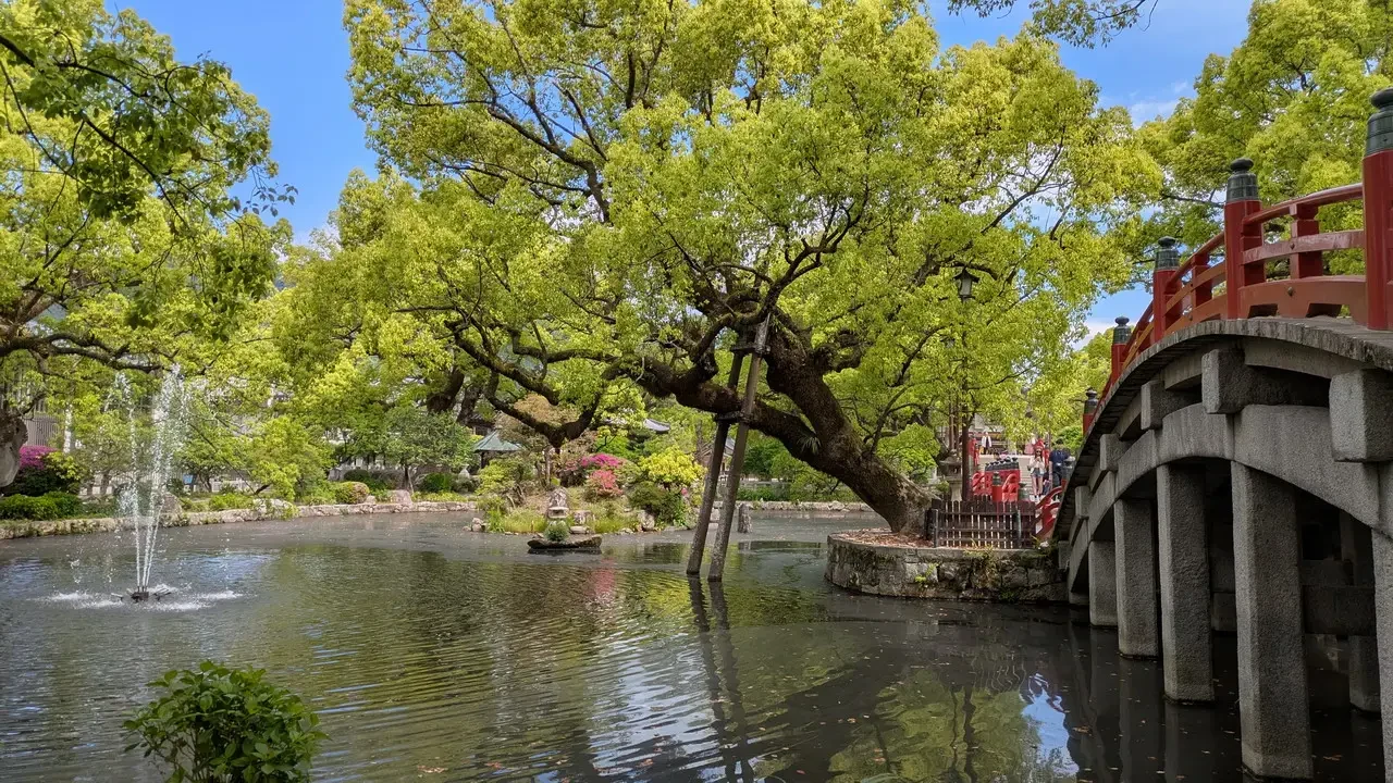 Un ponte rosso attraversa un corso d'acqua circondato da alberi frondosi in Giappone.