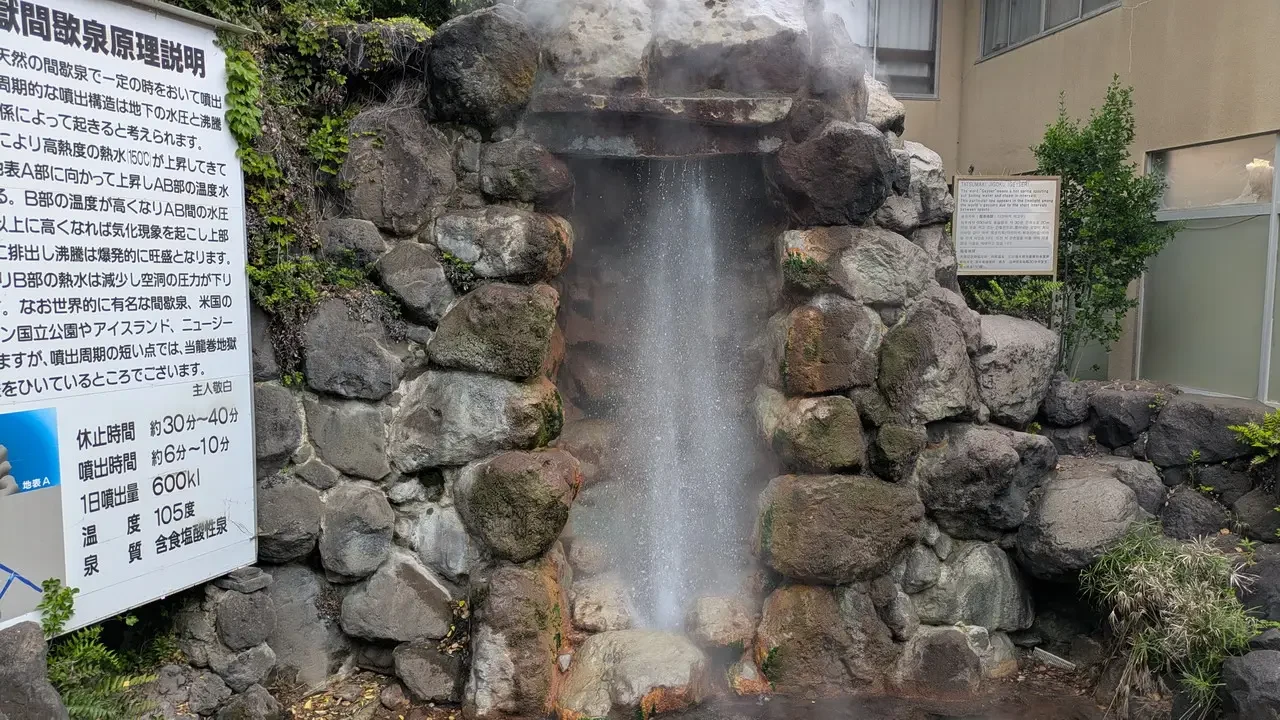Una cascata di acqua scorre su rocce in un giardino giapponese.