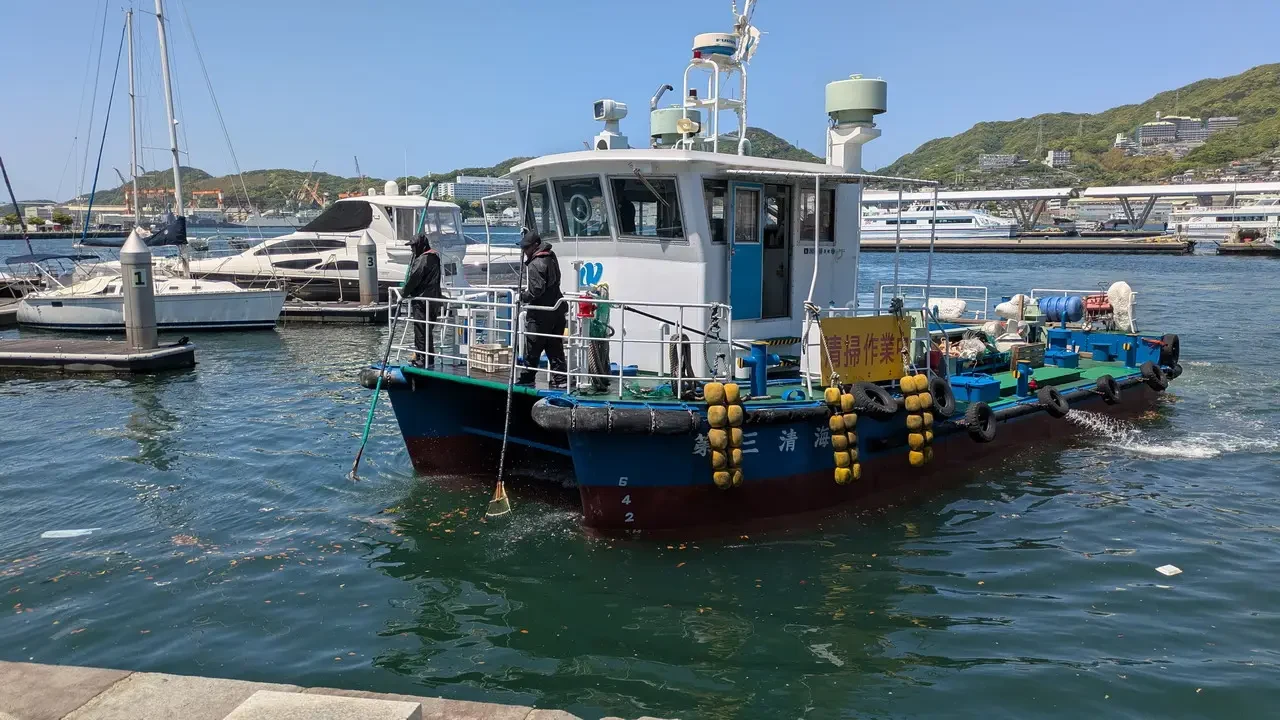 Una barca blu naviga in un porto giapponese sotto il sole.