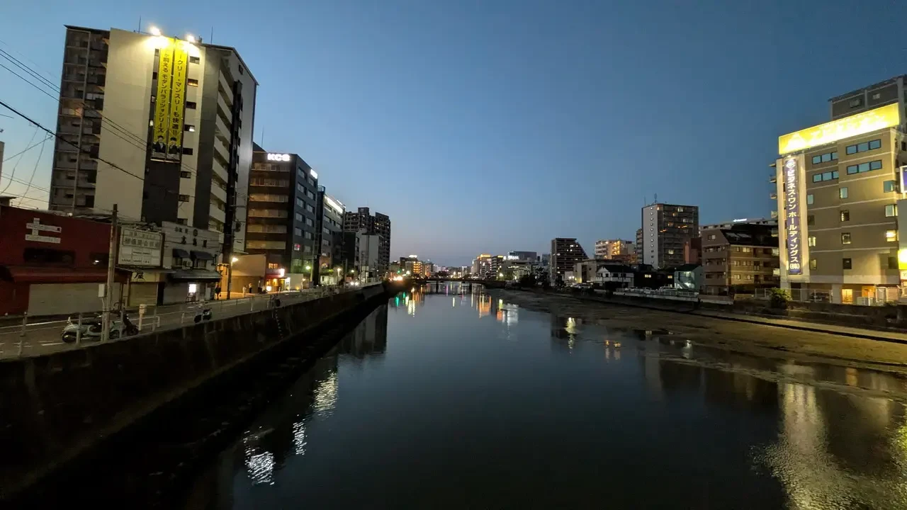 Una vista notturna di un fiume in una città giapponese illuminata.