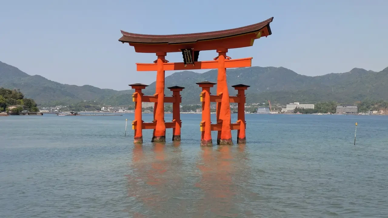 Un grande cancello torii rosso galleggia sull'acqua.