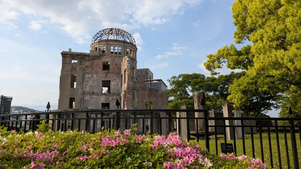 Il Memoriale della Pace di Hiroshima è visibile attraverso una recinzione e fiori in primo piano.