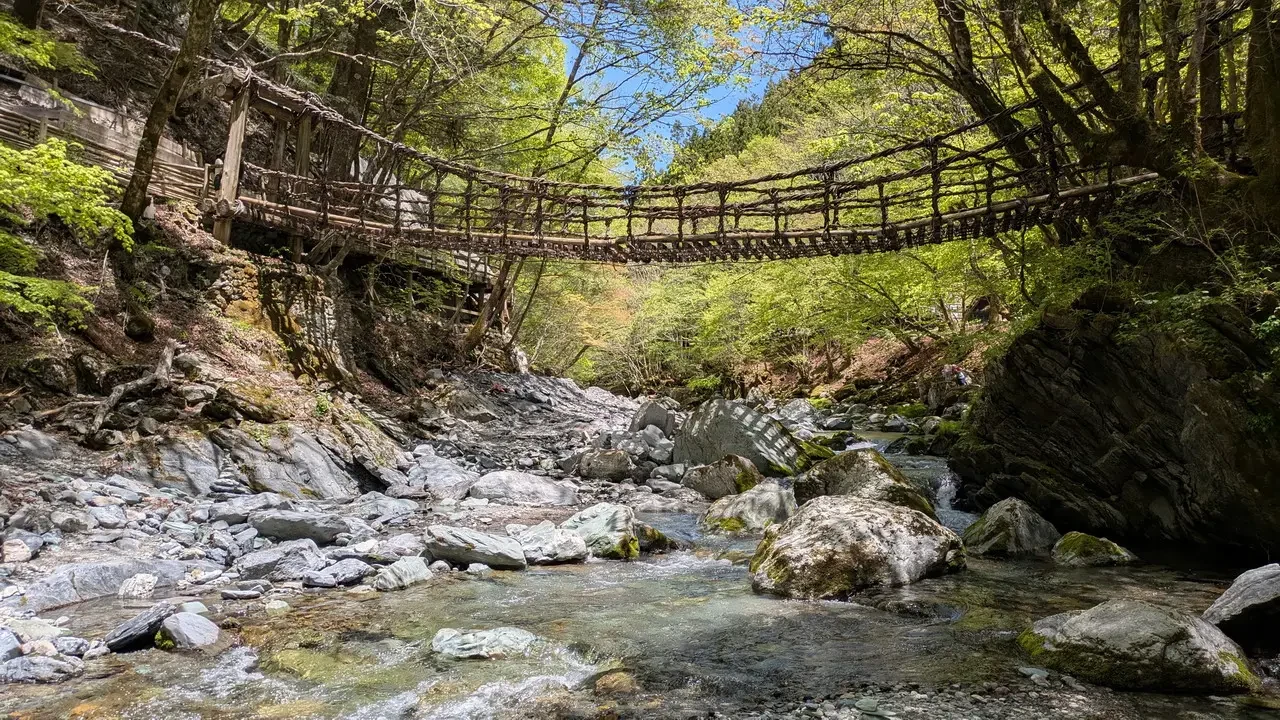 Ponte ligneo sopra un fiume roccioso nel Giappone.