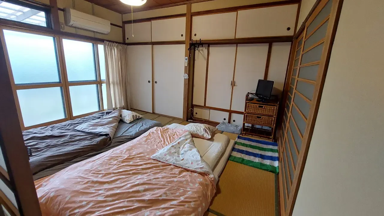 Interni di una tradizionale ryokan giapponese con letti a sorpasso e finestre panoramiche.