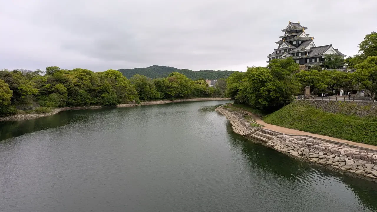 Giardino Koraku a Okayama con un ponte e una struttura tradizionale in legno.