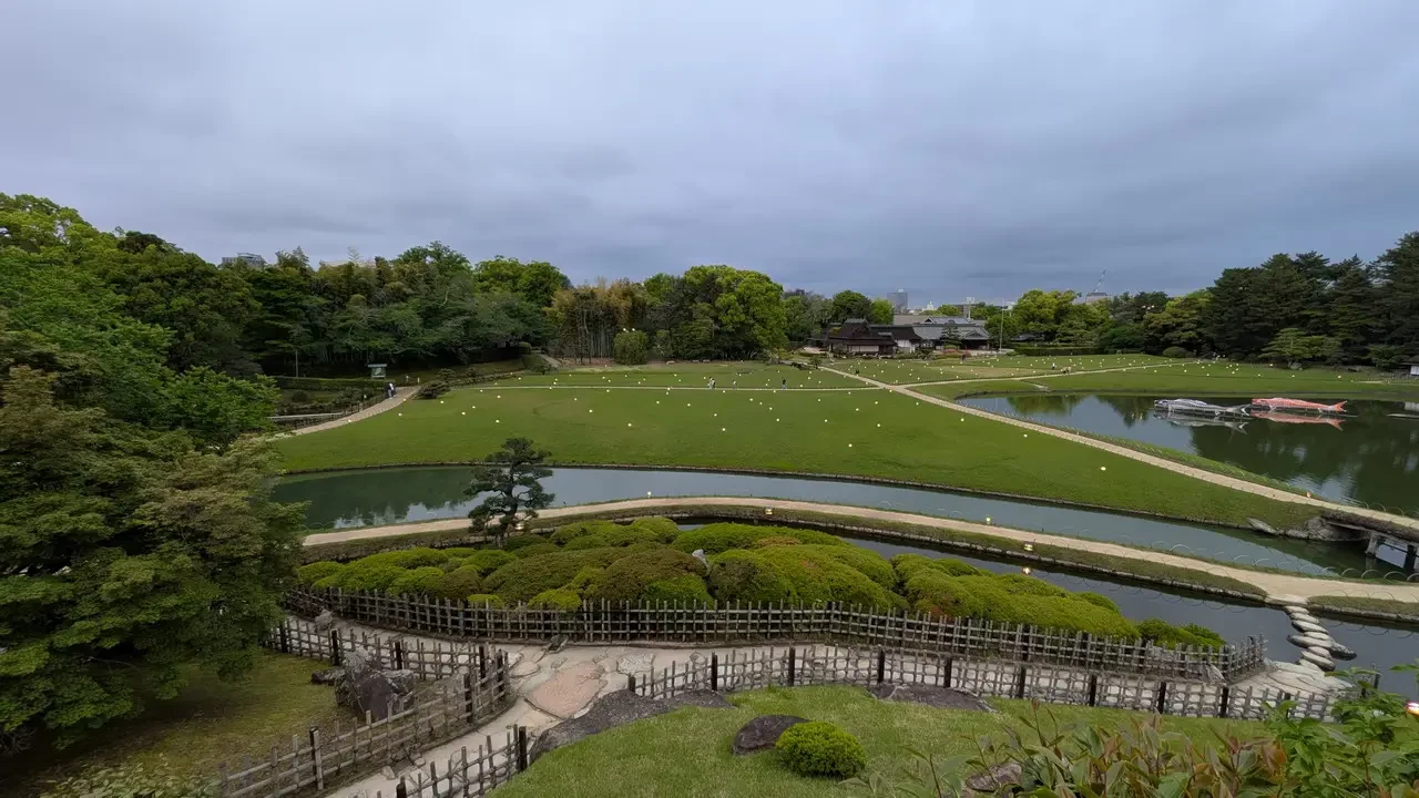 Giardino giapponese con elementi naturali e sentieri curvi sotto un cielo coperto.