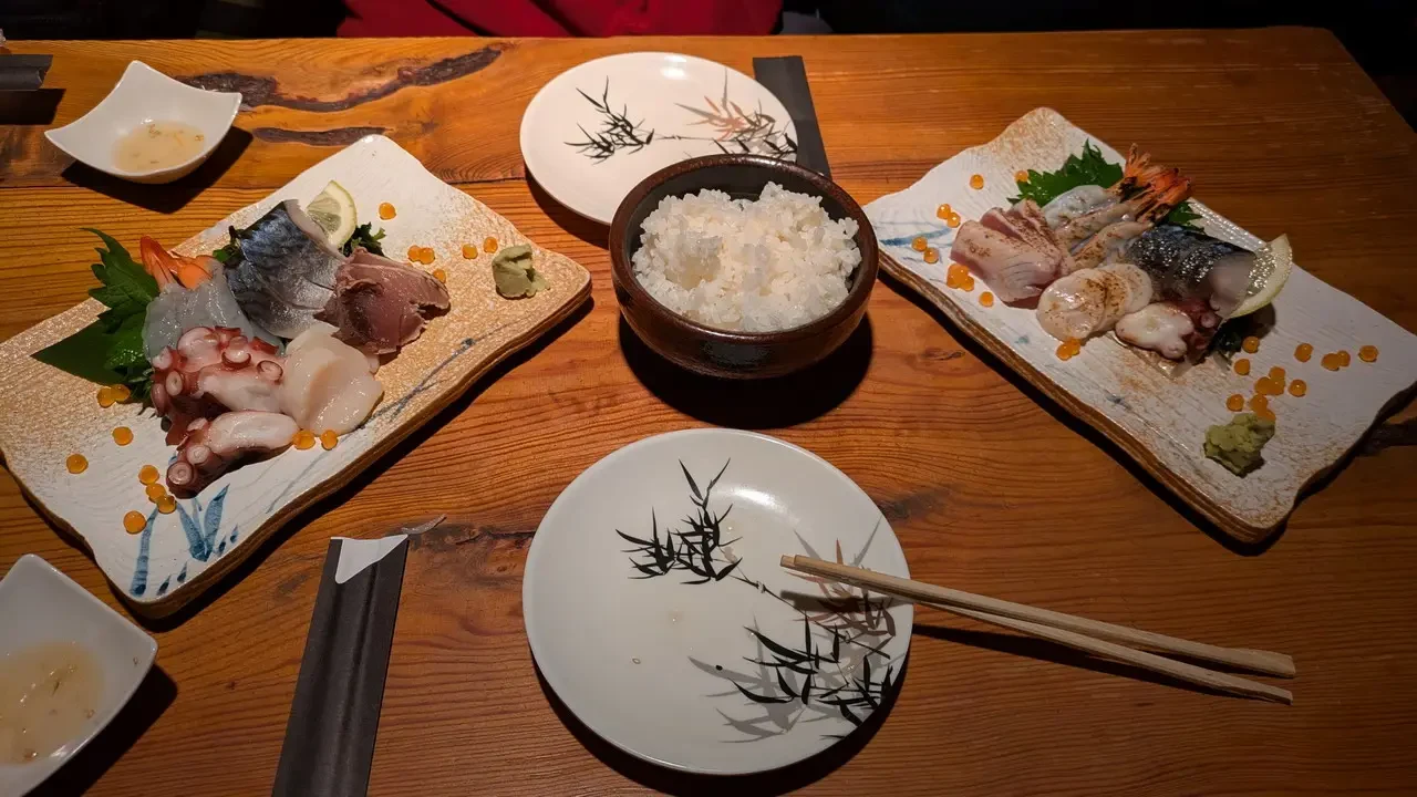 Un tavolo apparecchiato con sashimi e riso in stile giapponese per una cena.