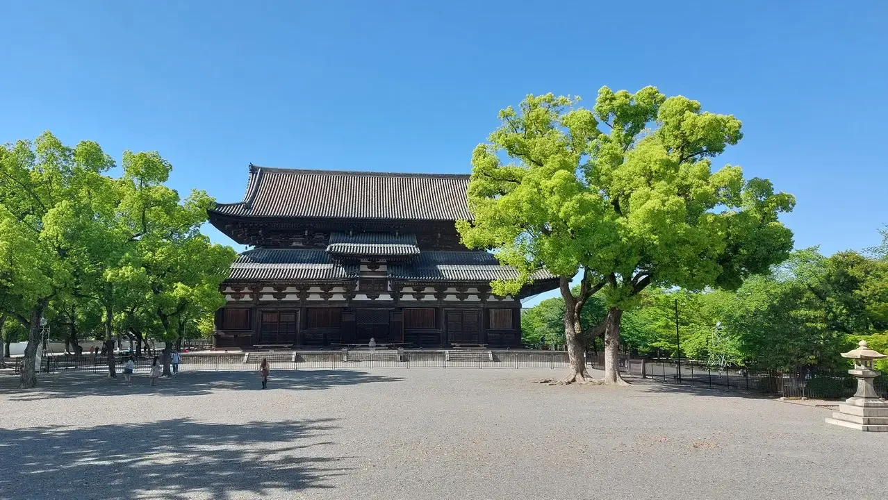Vista frontale del tempio Kiyomizu-dera con alberi lussureggianti in primo piano.