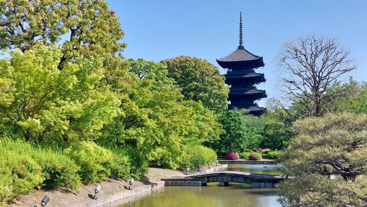 Pagoda in legno su un'isola circondata da vegetazione lussureggiante e un ponte in pietra.