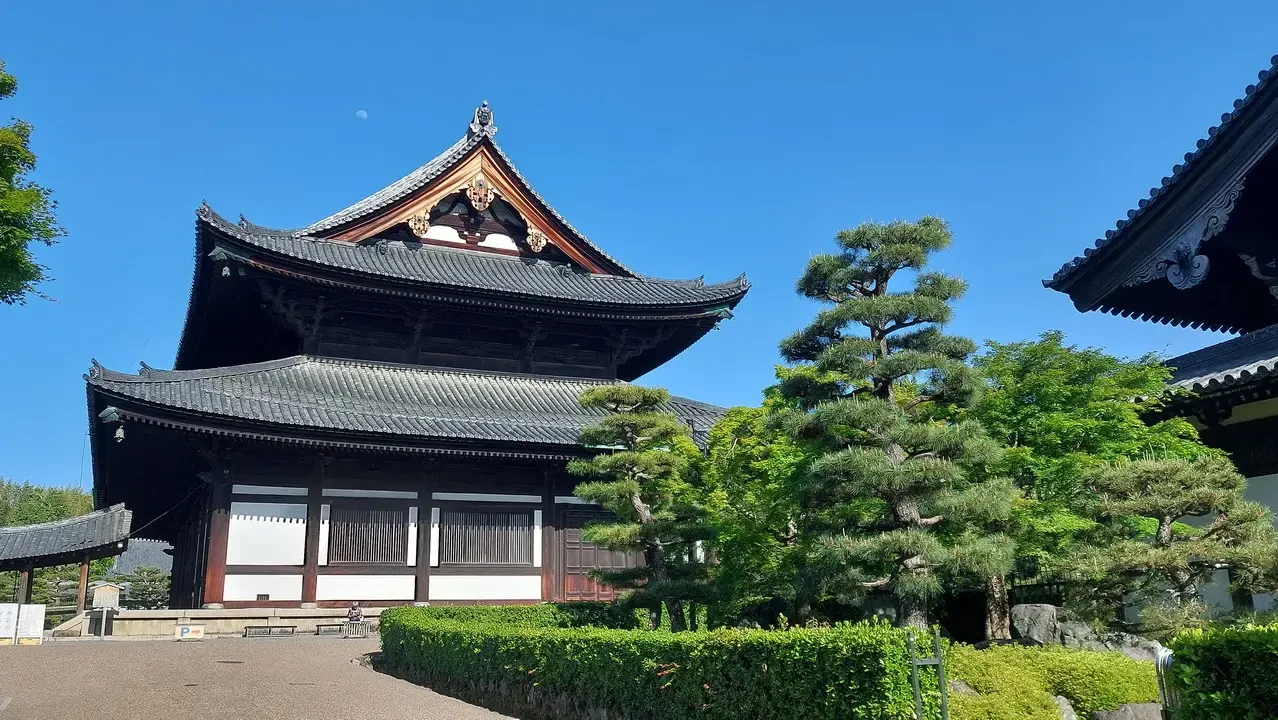 Vista esterna del tempio Tofuku-ji a Kyoto con alberi verdi in primo piano.