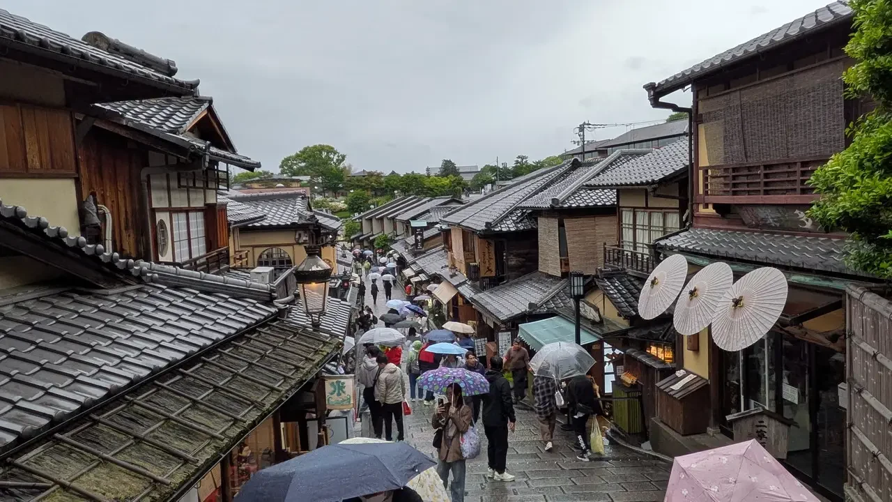 Una strada pedonale tradizionale a Kyoto con tetti in tegole e negozi.