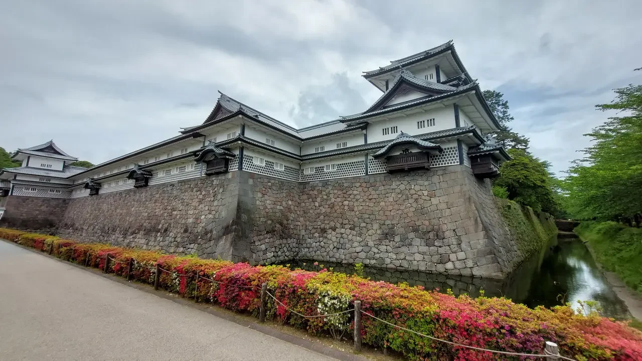 Castello di Kanazawa con mura in pietra e giardino lussureggiante.