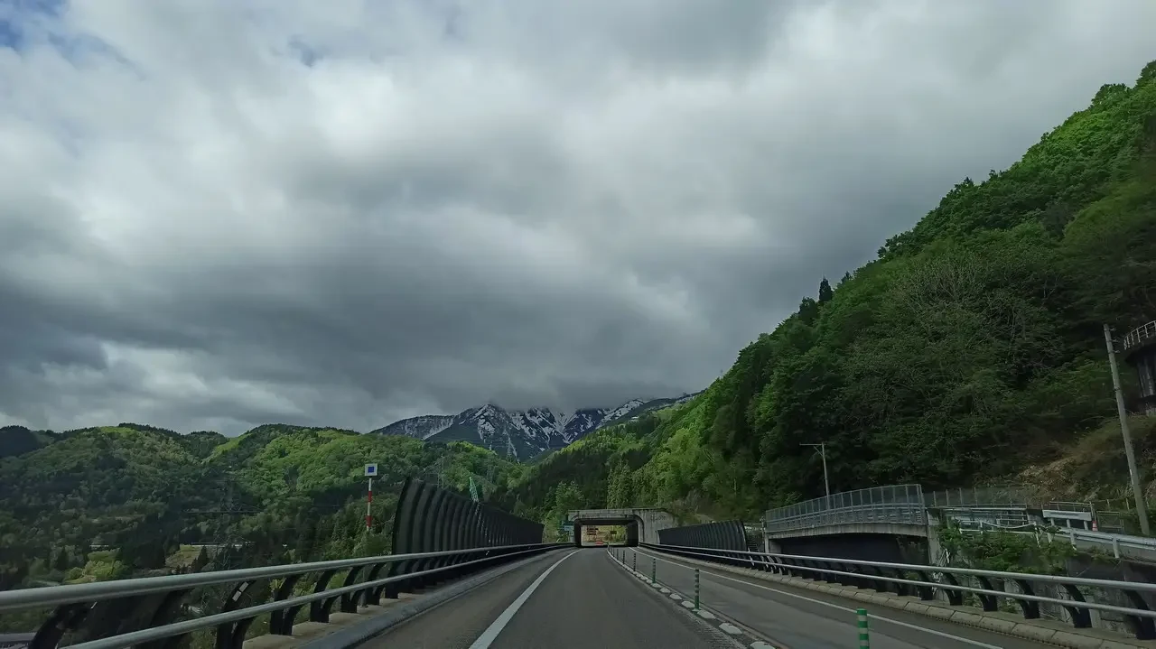 Un paesaggio montano verde e nuvoloso lungo una strada panoramica in Giappone.