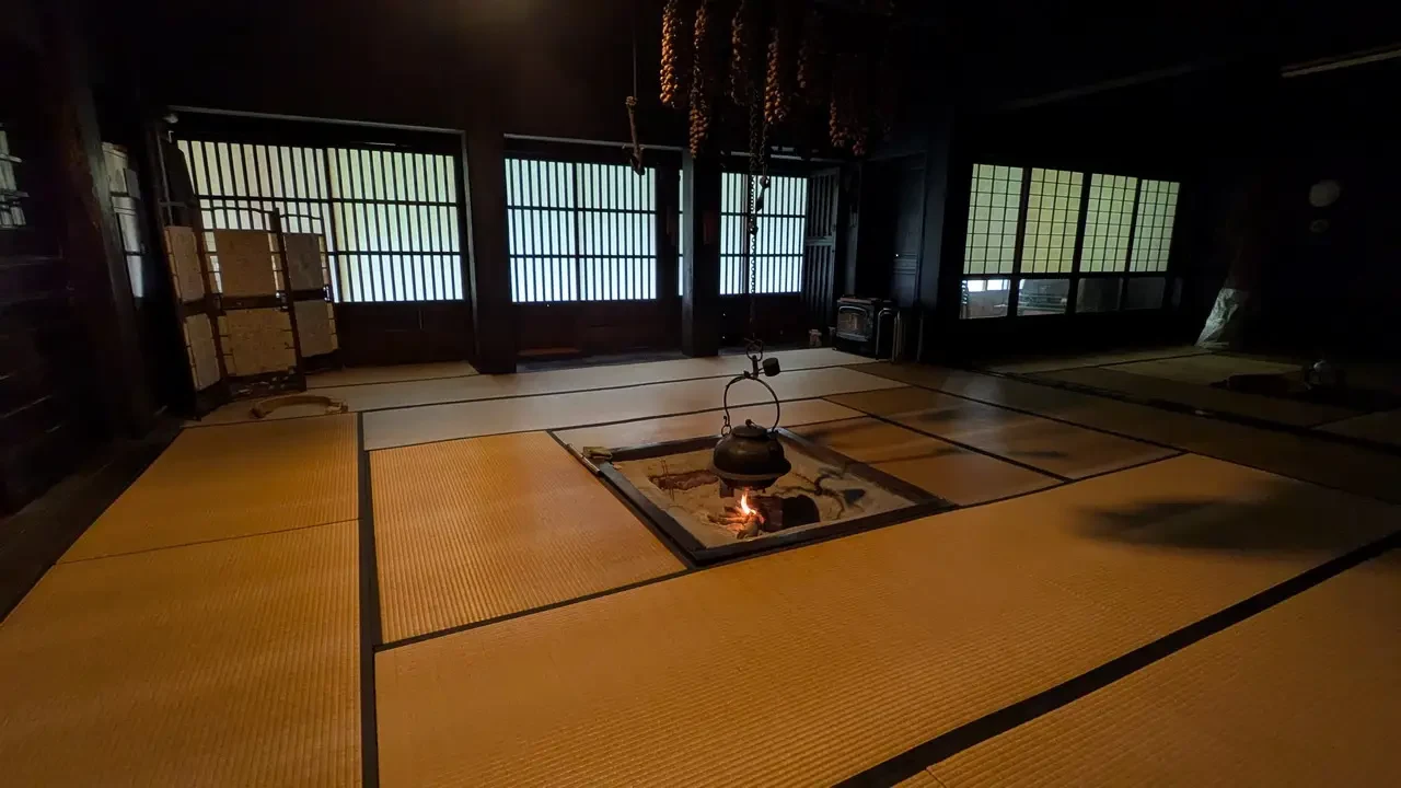 Interno tradizionale giapponese con pavimento in tatami e camino a pavimento.
